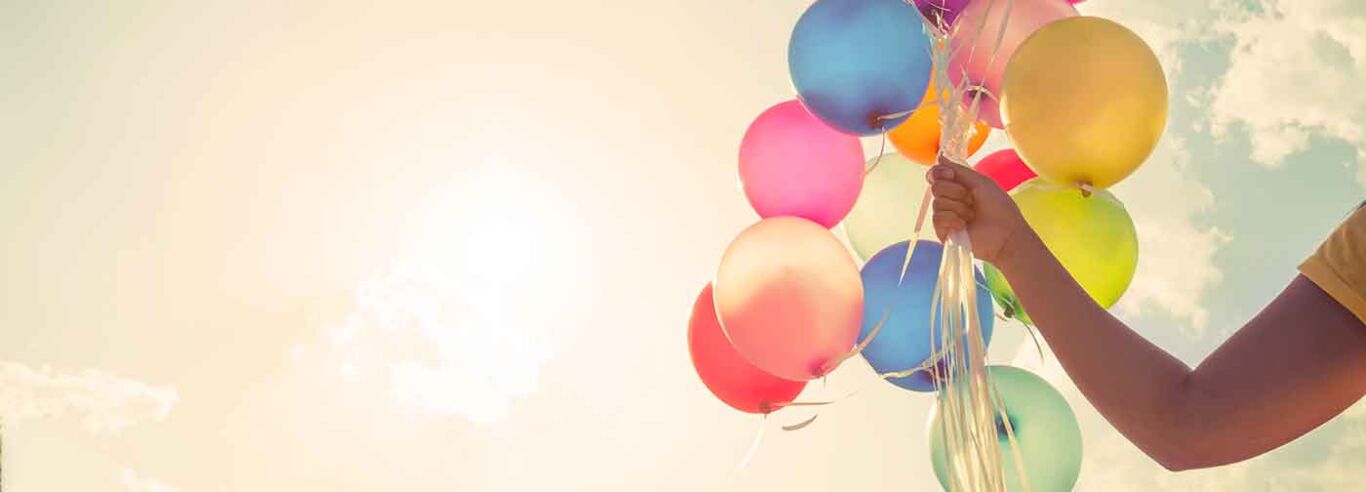 Campus Absolventen Hand hält mehrere bunte Luftballons, von der Sonne beschienen